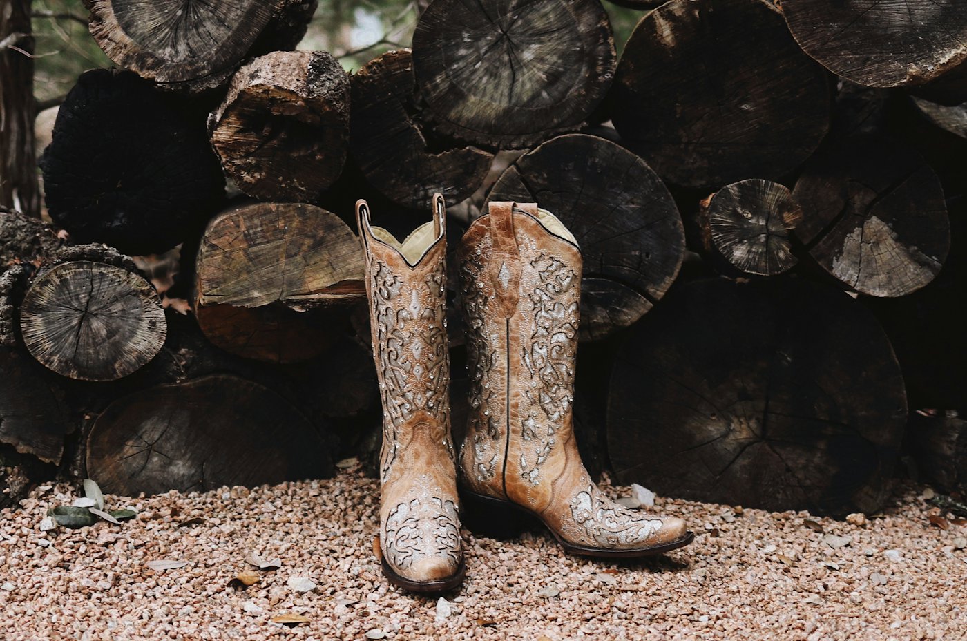 Leather cowboy boots by a woodpile