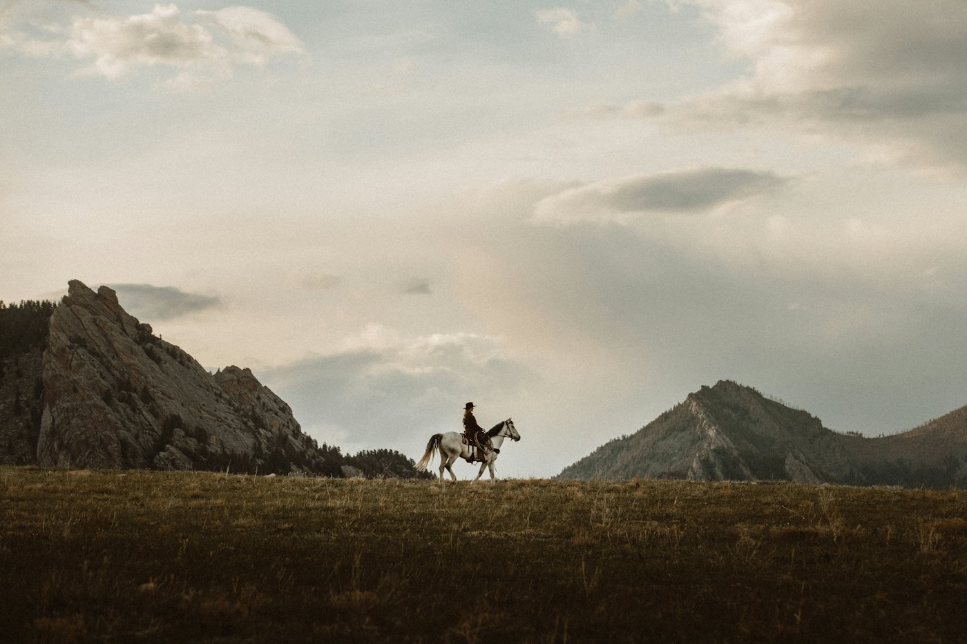 Two riders on horseback crossing open land